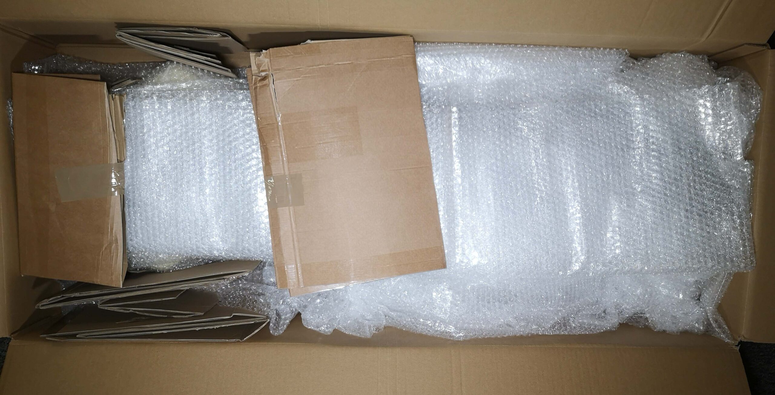 Ein Gitarrenkarton, der Mit gut verpackter Gitarre und viel Polstermaterial gefüllt ist.